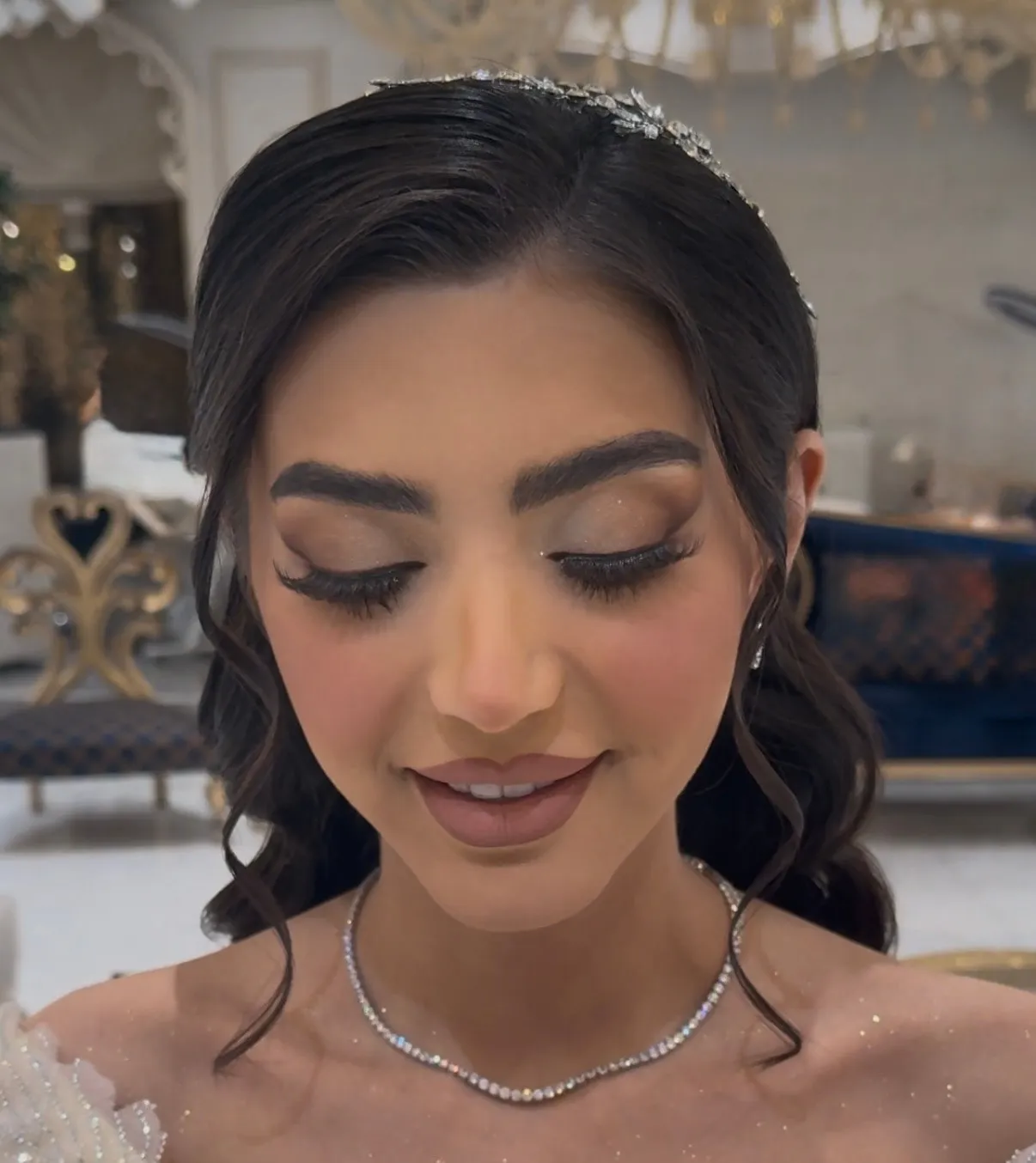 Bride with soft glam makeup, fluttery lashes, a rosy nude lip and a delicate crystal headpiece