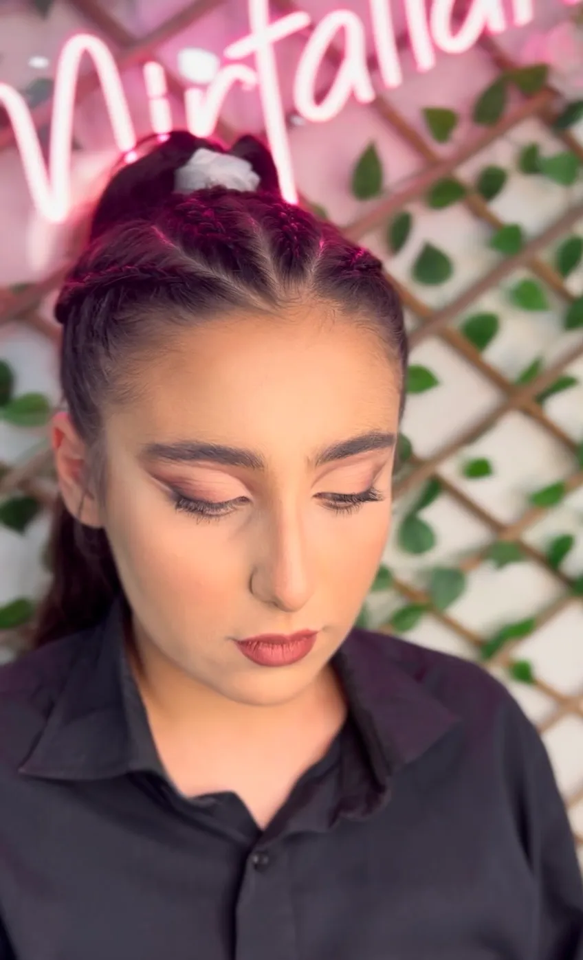 Glam look with a soft winged eye, sculpted brows and a mauve lip beside a braided ponytail