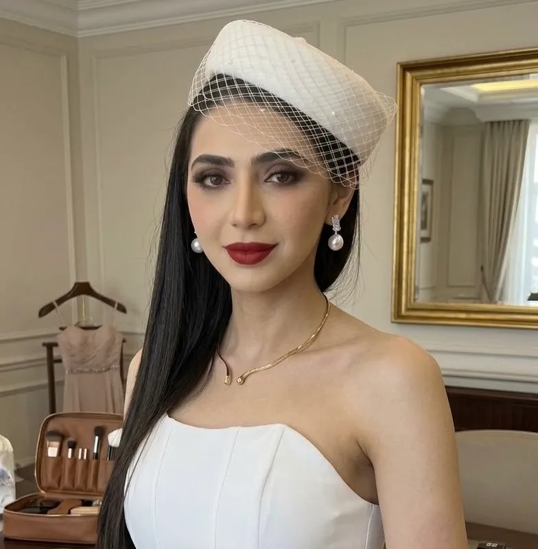 Bride in a birdcage veil hat with soft smoky eyes, a deep red lip and pearl earrings